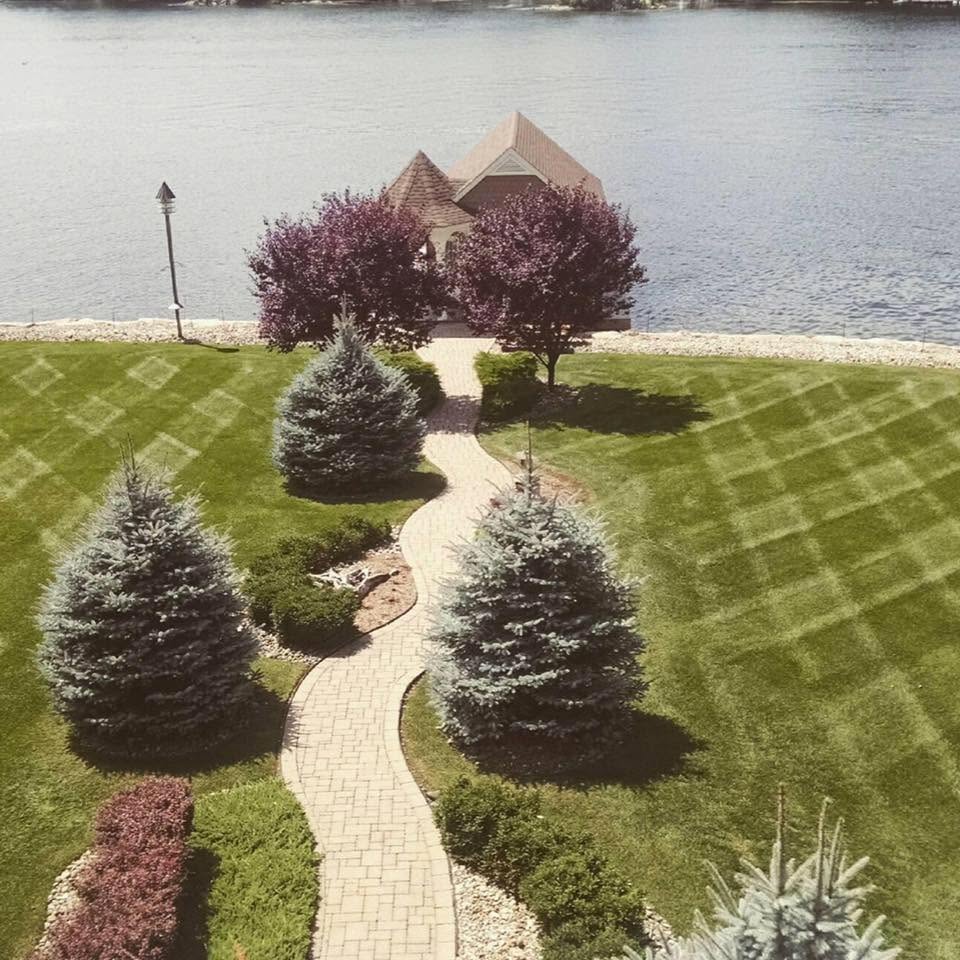 Lakefront paver walkway, blue spruce plantings and checkerboard-striped lawn